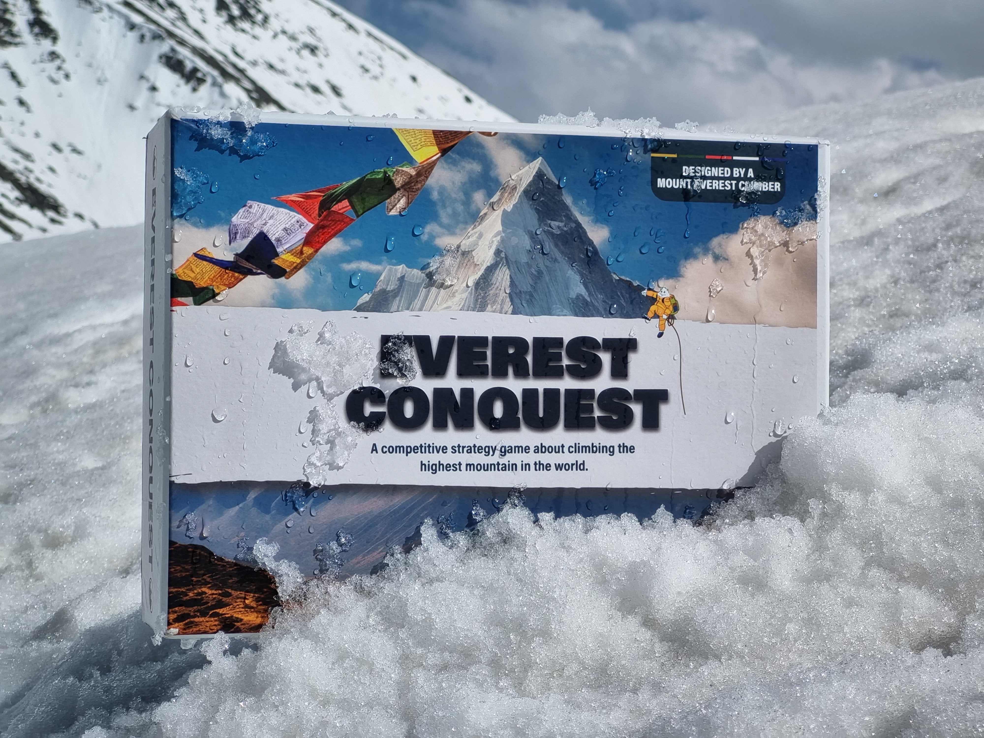 Everest Conquest board game box resting in fresh mountain snow
